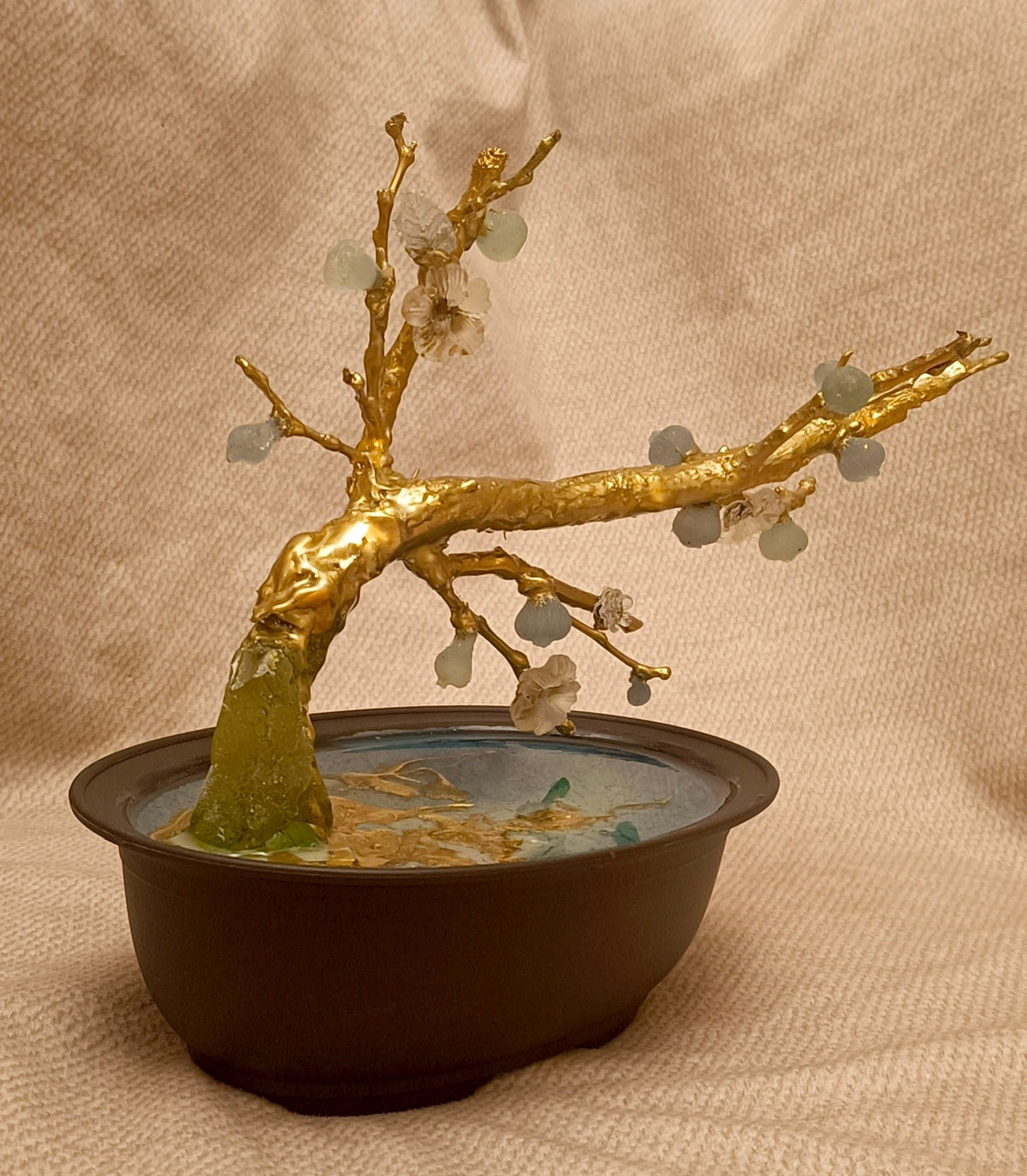 Gold-colored textured trunk and blue glasswork in pot